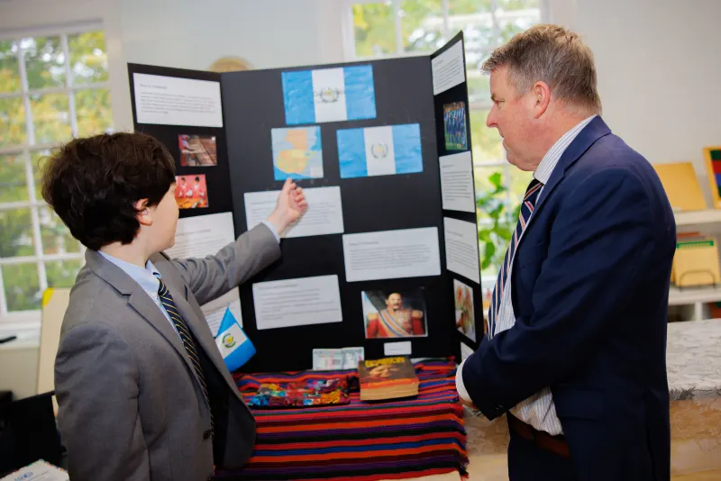 A student is talking a teacher through their project exhibit.