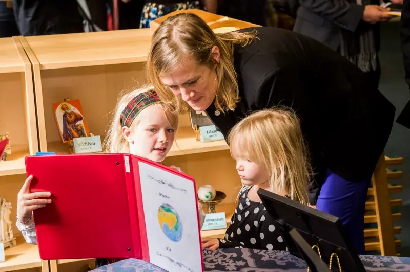 A child is showing a teacher her project work.