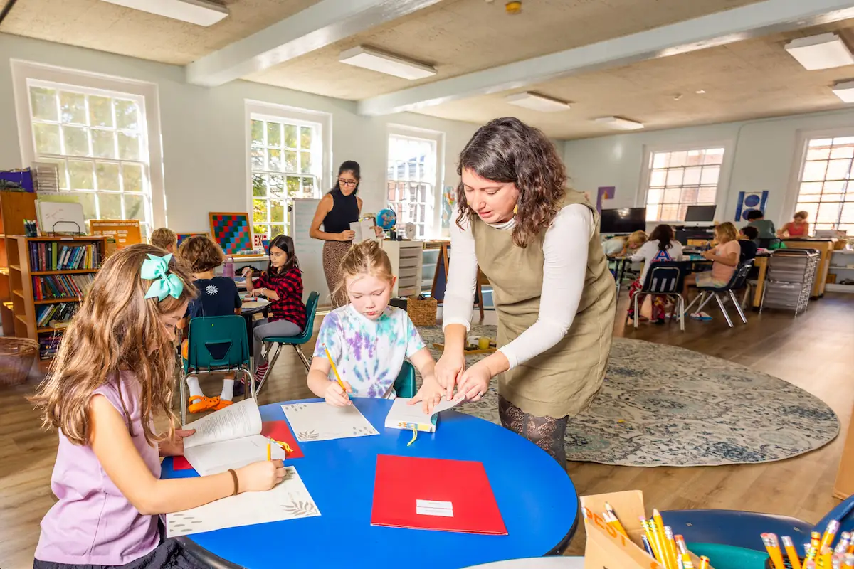 Students sit at different round tables working on their projects