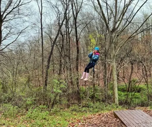 A student in a helmet is on an outdoor adventure course.