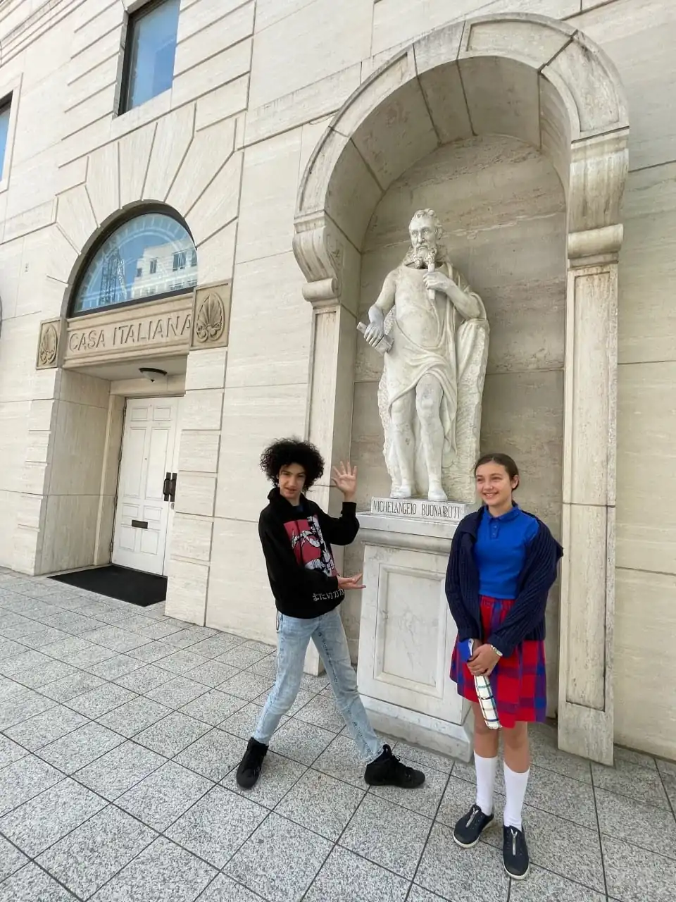 Two students pose in front of a statue at the Casa Italiana