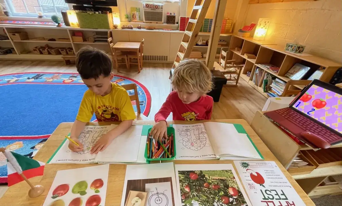 Two students are colouring in using coloured pencils