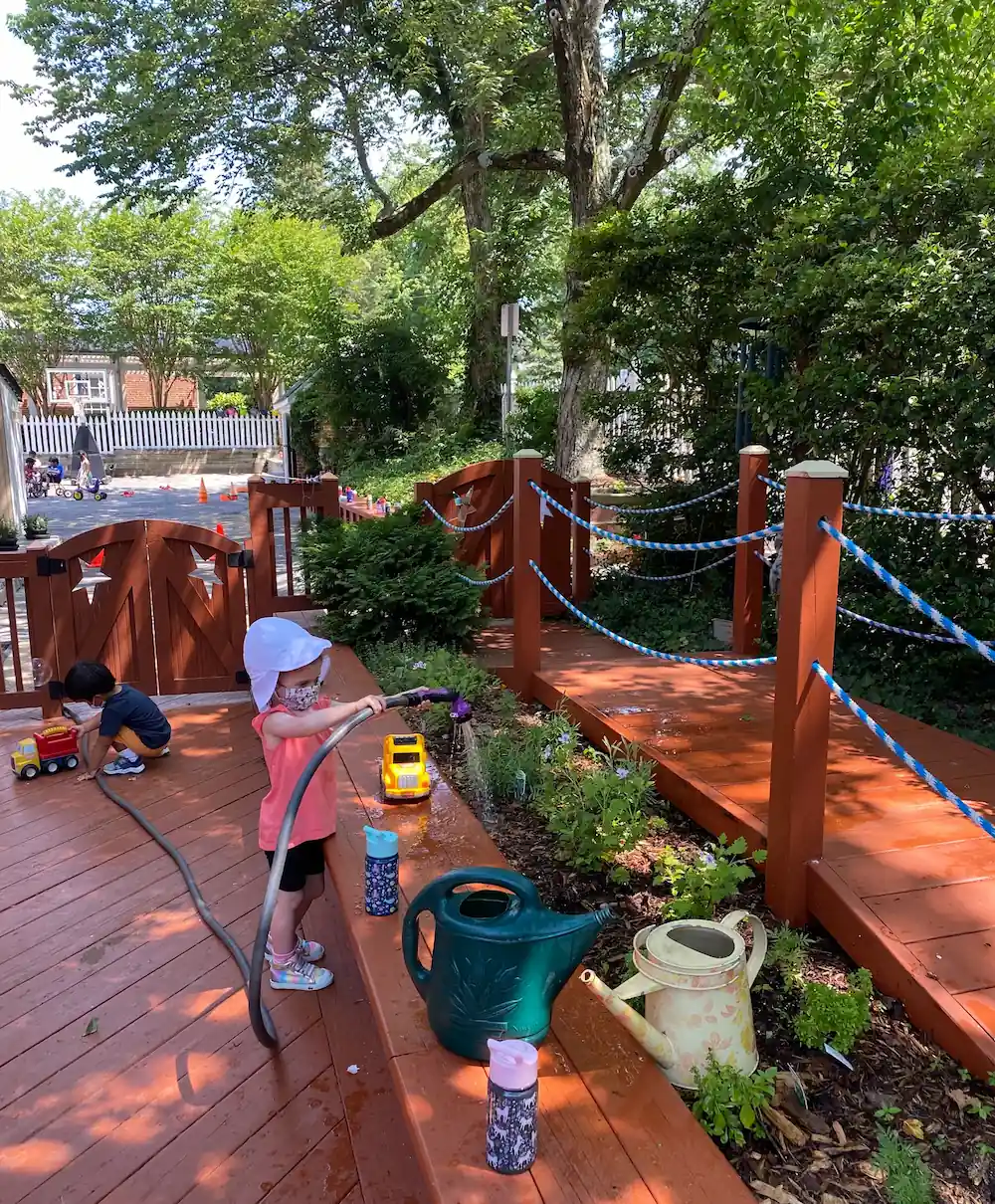 A young student is watering plants in the garden.