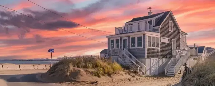 Photo of a house on the beach with a beautiful pink sunset