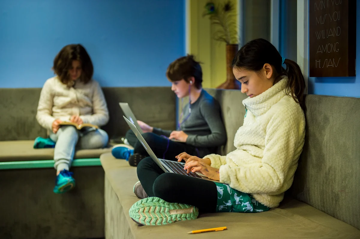 Photo of three students quietly sitting on the bleachers immersed in their work.