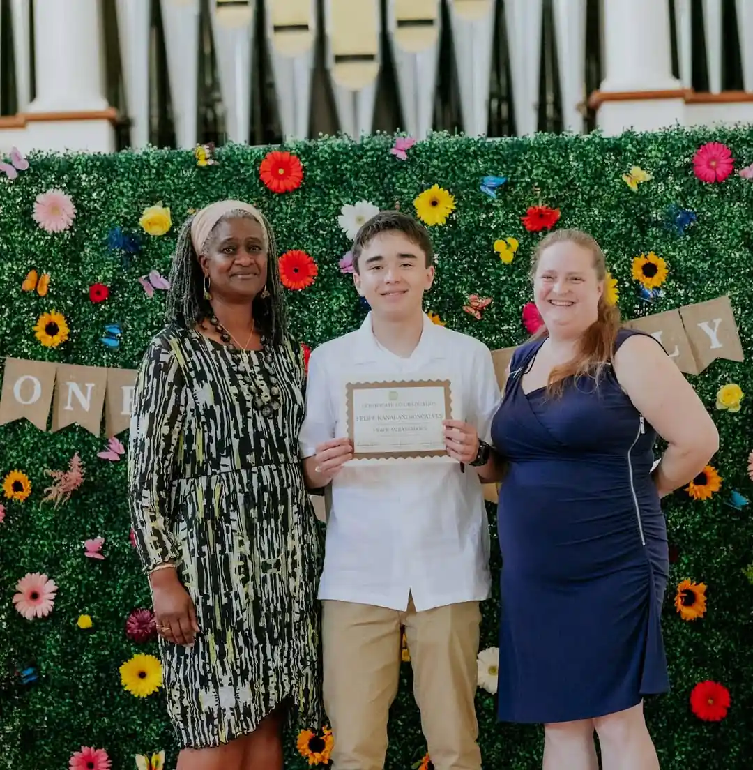 Photo showing a graduating student with two proud teachers.