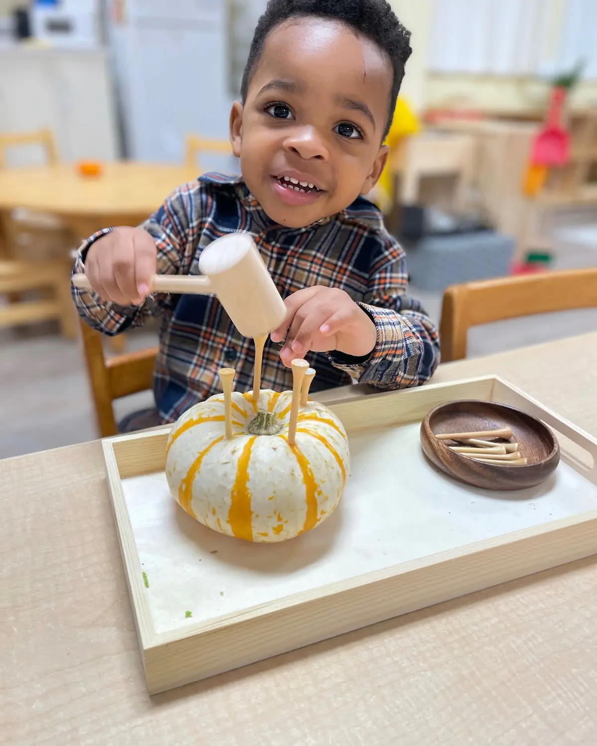 Photo of a young student hammering candle-holders into a pumpkin.