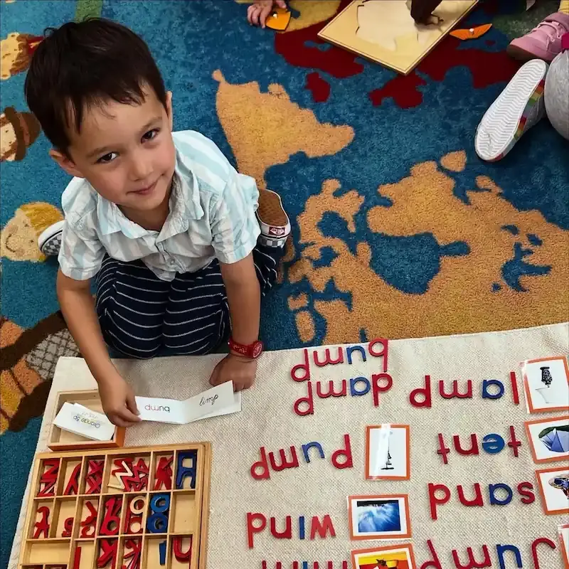 A student is playing with wooden coloured letters on the rug