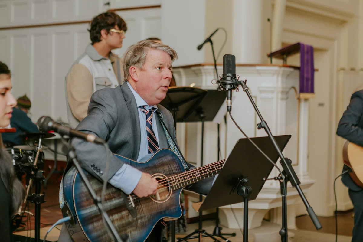 The school founder is playing a semi-acoustic guitar.