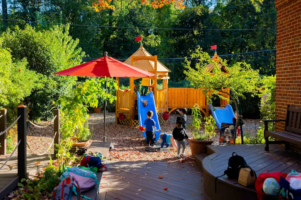 Photo of an outdoor play area with slides and green trees.