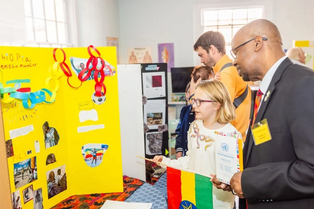 A student is showing a display of work to a visiting adult