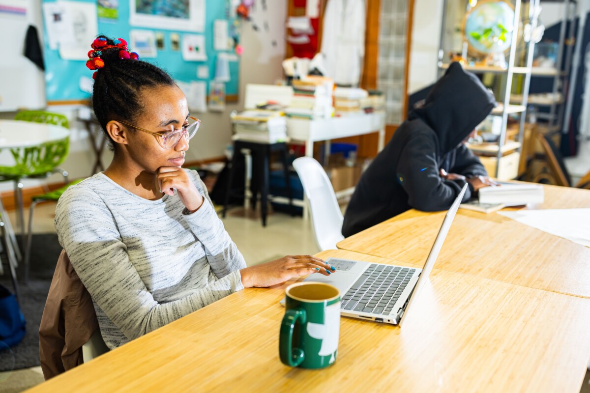 student seated and working on laptop